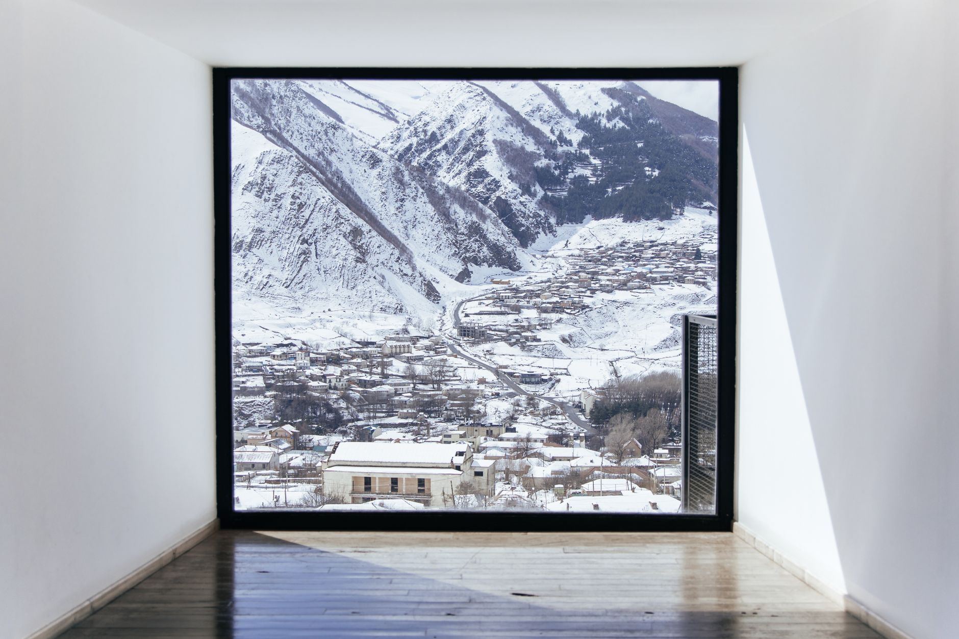 A large window framing a snowy mountain town