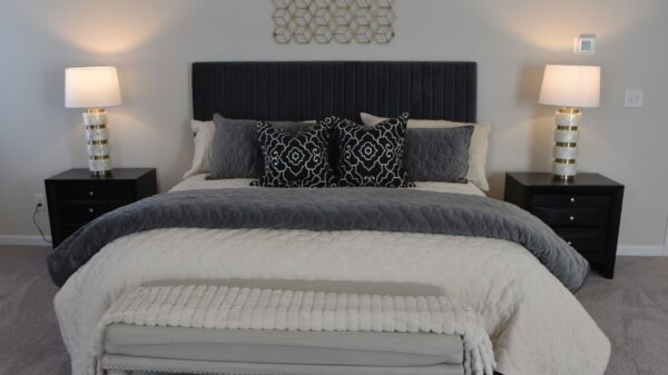 A made bed with a gray blanket and lamps