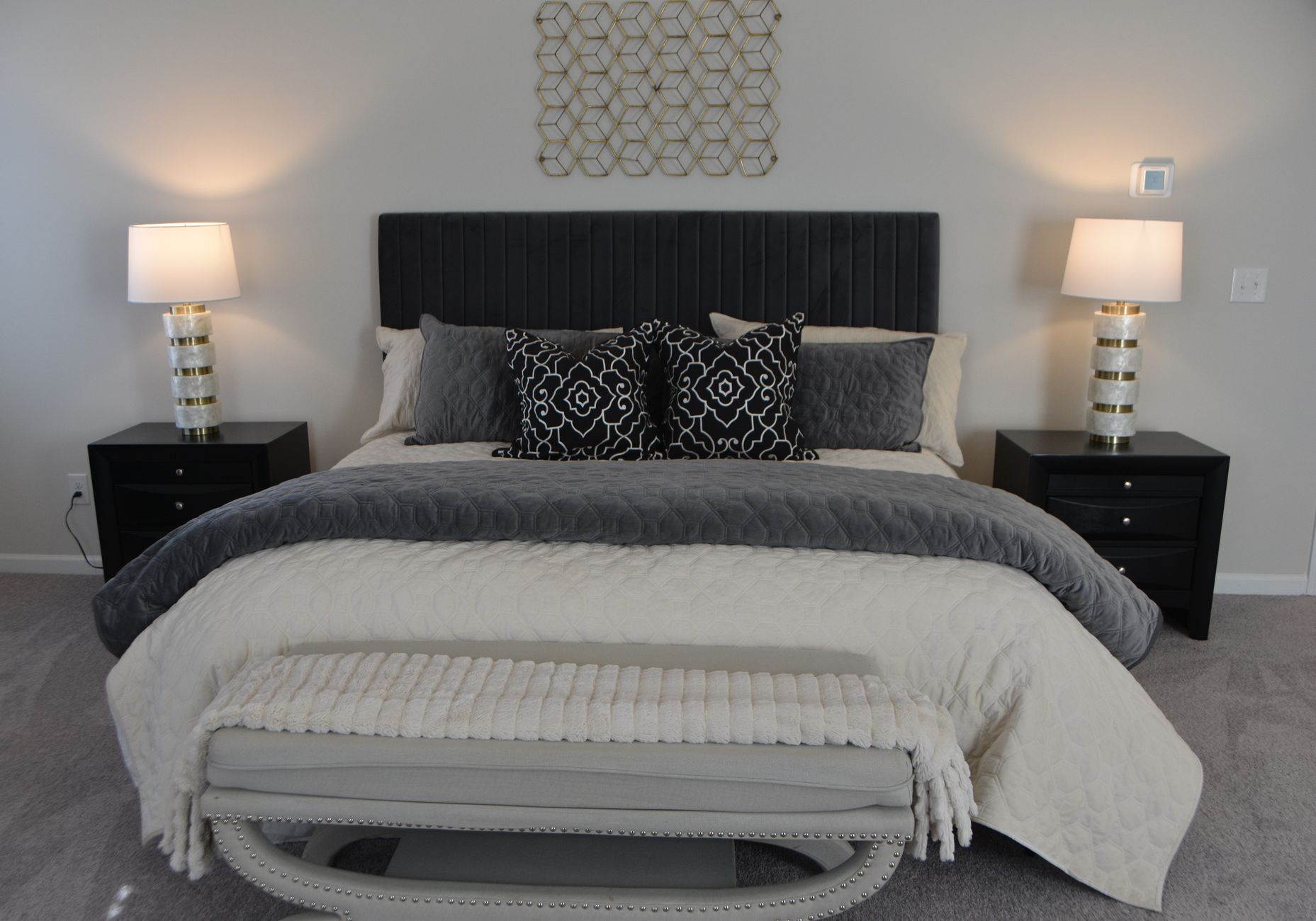 A made bed with a gray blanket and lamps