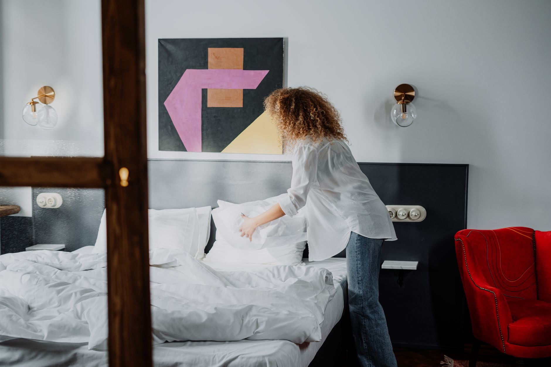 A woman making a bed in a bright room