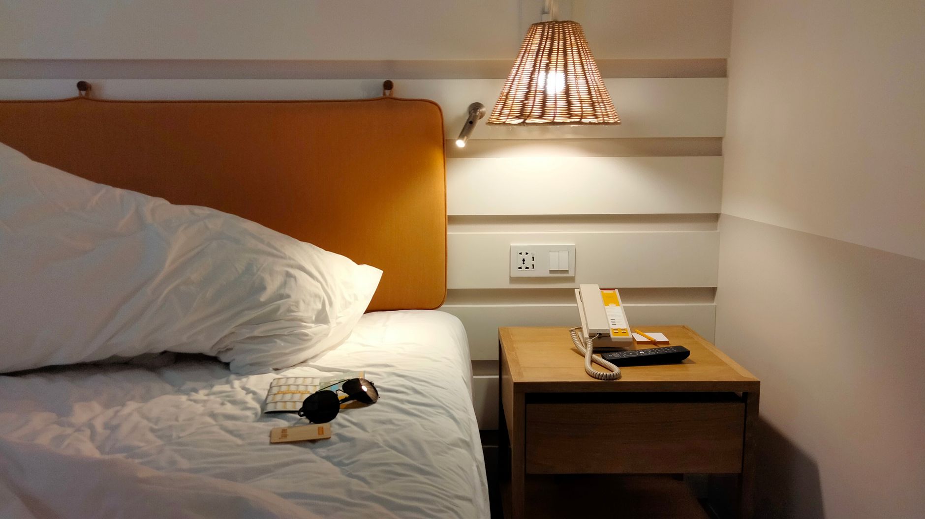 A bed lit by a pendant lamp