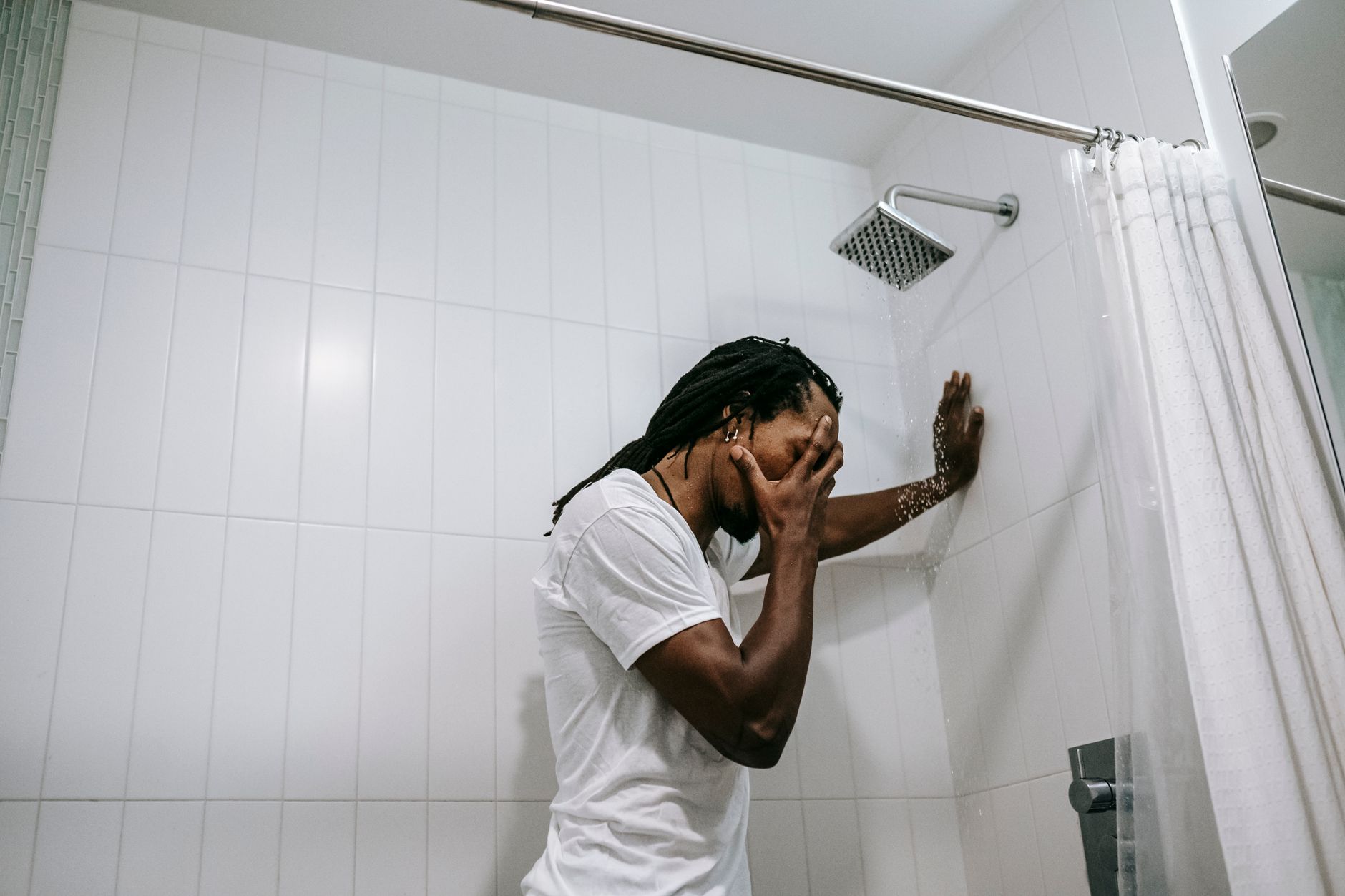 A man leaning on the wall in a shower