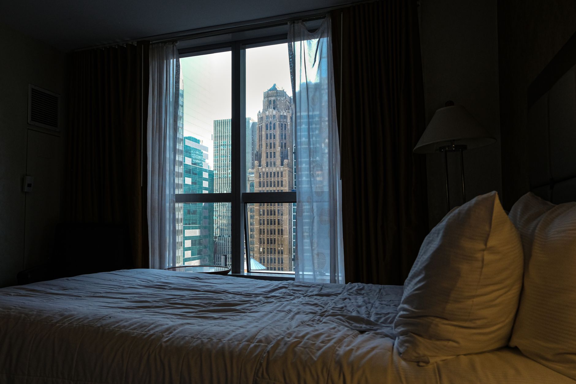 A dark bedroom with a city-view window