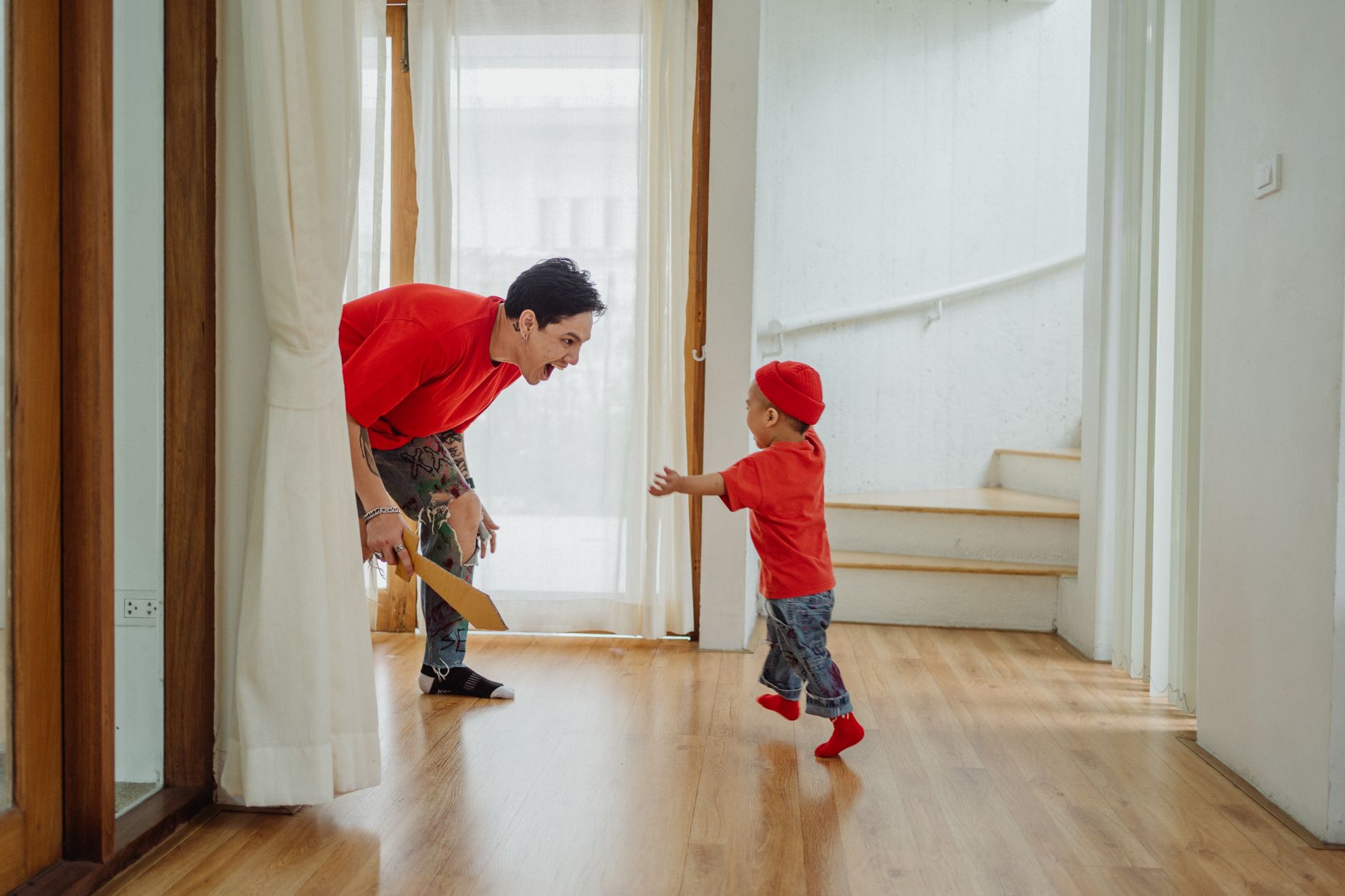 A father and toddler by a sheer-curtained door