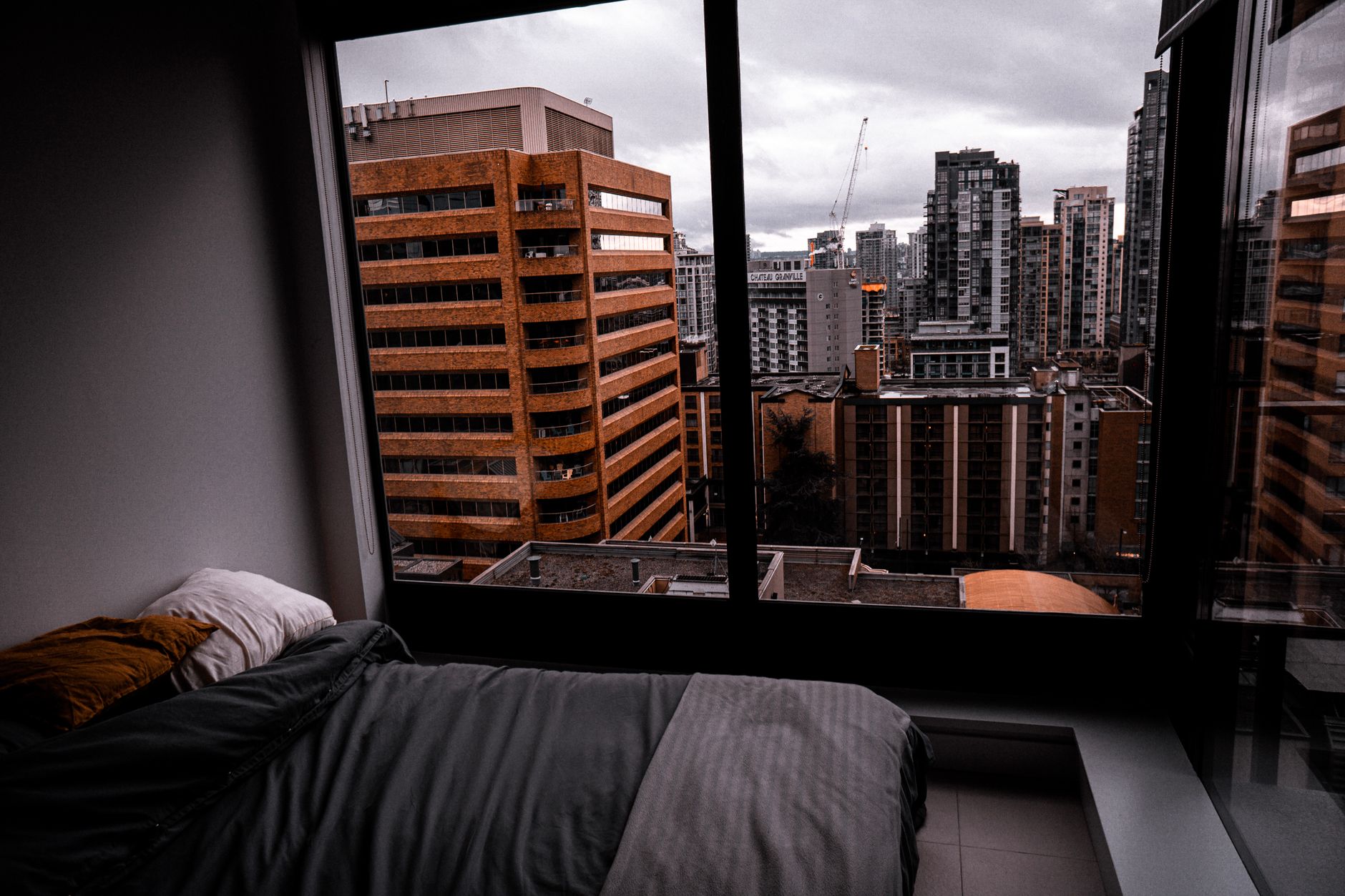 A bed by a large city-view window