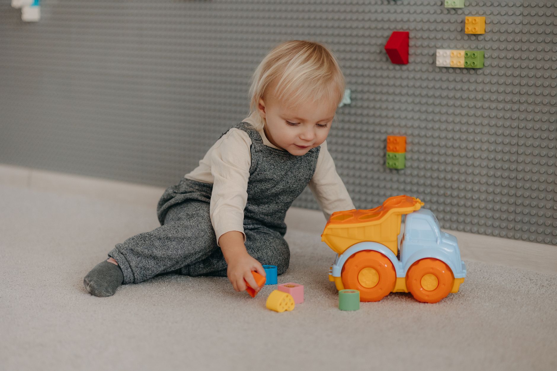 A toddler playing with a toy dump truck