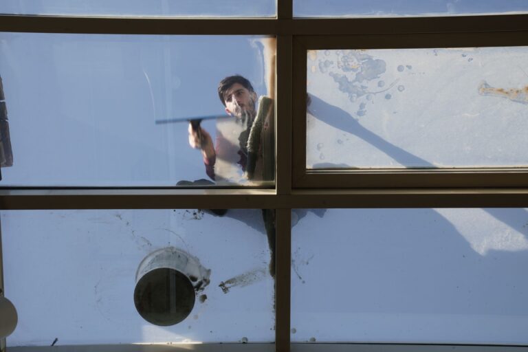 Best window vacuum: a man squeegeeing a large glass window