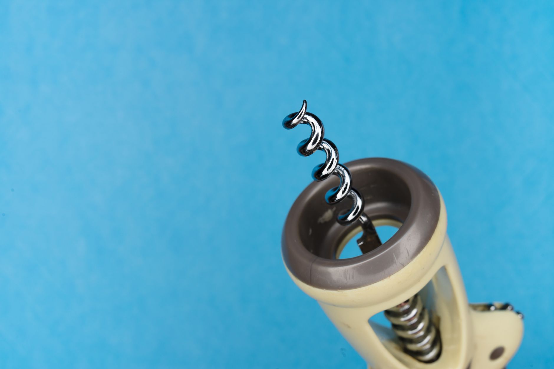 A corkscrew next to a bottle of wine